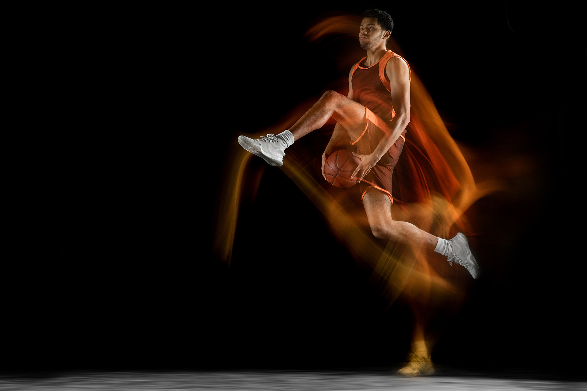 Fire. Young arabian muscular basketball player in action, motion isolated on black background in mixed light. Concept of sport, movement, energy and dynamic, healthy lifestyle. Training, practicing.